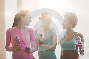 Happy women with bottles of water in gym