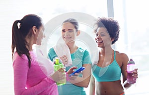 Happy women with bottles of water in gym