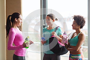 Happy women with bottles of water in gym