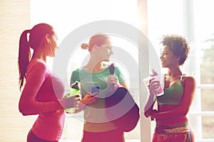 Happy women with bottles of water in gym