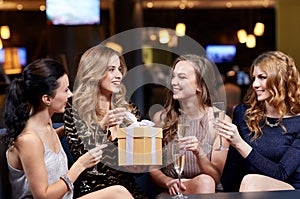 Happy women with champagne and gift at night club