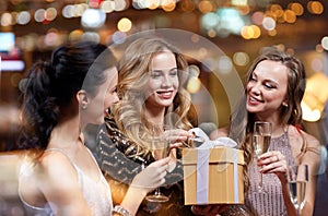 Happy women with champagne and gift at night club
