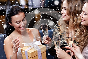 Happy women with champagne and gift at night club