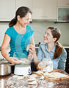 Happy women cooking pies with electric steamer