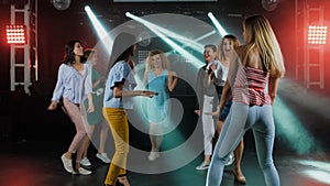 Happy women dancing to the music of party with her other girl friends on the dance floor of a fashionable night club in