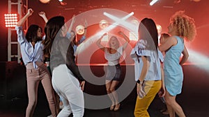 Happy women dancing to the music of party with her other girl friends on the dance floor of a fashionable night club in