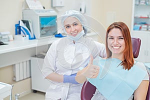 Happy women a dentist and patient after treating teeth at the dental office, smiling and looking towards the camera