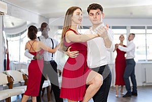 Happy woman enjoying impassioned merengue with male partner in dance room during party. Social dancing concept photo