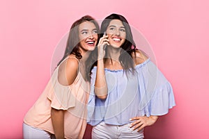 Happy women enjoying phone talk on pink background