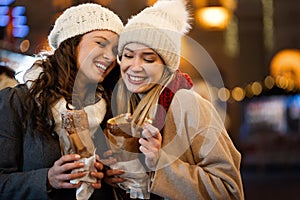 Happy women friends enjoying christmas market and having fun together outdoors.