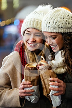 Happy women friends enjoying christmas market and having fun together outdoors.