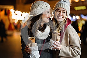 Happy women friends enjoying christmas market and having fun together outdoors.