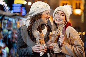 Happy women friends enjoying time together in the city with christmas decorations outdoor