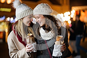 Happy women friends enjoying time together in the city with christmas decorations outdoor