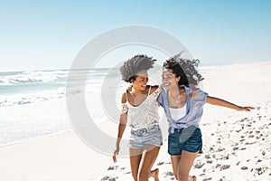 Happy women friends running on summer beach with copy space