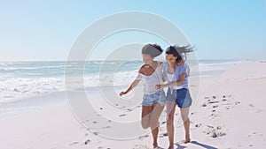 Happy women friends running together on summer beach