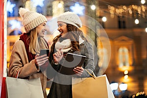 Happy women friends shopping Christmas gifts in the city. People holiday sale happiness concept
