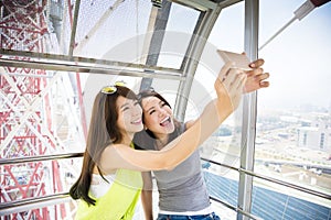 Happy women girlfriends taking a selfie in ferris wheel