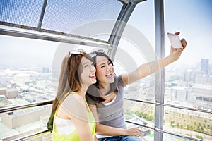 Happy women girlfriends taking a selfie in ferris wheel