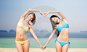 Happy women making heart shape on summer beach