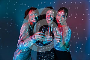 Happy women posing isolated with disco ball lights holding glasses with champagne