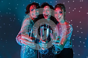 Happy women posing isolated with disco ball lights holding glasses with champagne