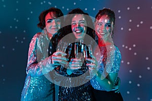 Happy women posing isolated with disco ball lights holding glasses with champagne