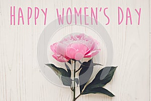 Happy women`s day text on pink peonies bouquet on rustic white w
