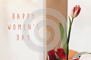 Happy women`s day text on pink tulip in vase on window in soft m