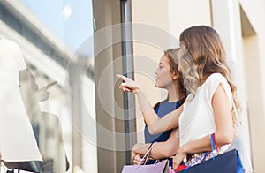 Happy women with shopping bags at shop window