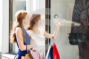 Happy women with shopping bags at shop window