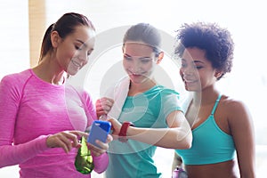 Happy women showing time on wrist watch in gym