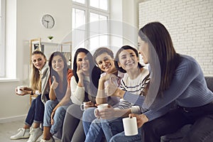 Happy women sitting on couch, drinking coffee, sharing good news and supporting each other