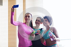 Happy women with smartphone taking selfie in gym