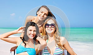 Happy women sunbathing on chairs over summer beach