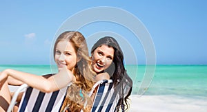 Happy women sunbathing on chairs over summer beach