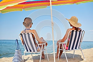 Happy women sunbathing in lounges on beach