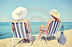 Happy women sunbathing in lounges on beach