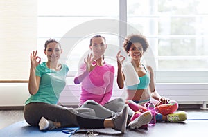 Happy women with water showing ok sign in gym