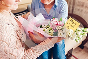 Happy Womens Day, 8 March gift. Woman holds greeting card with blooming spring yellow blue flowers at home