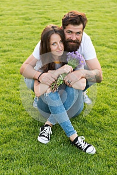 Happy womens day. Bearded man give flowers to sexy woman. Happy couple in love on green grass. Celebrating womens day