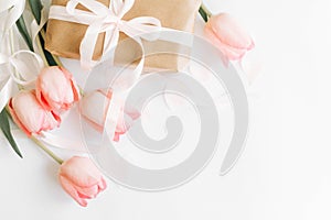 Happy womens day. Pink tulips flat lay with ribbon and gift box on white background, space for text. Stylish soft image. Greeting