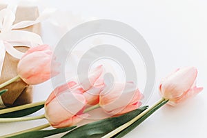 Happy womens day. Pink tulips and gift box with ribbon on white background. Stylish tender image.  Greeting card with space for