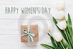 happy womens day text sign on stylish craft present box and tulips on white wooden rustic background. flat lay with flowers and g