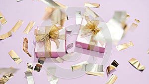 Happy womens day. Top view of two small wrapped gift boxes with golden bows on pastel pink background