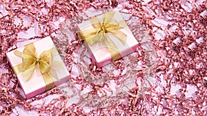 Happy Womens Day. Top view of two small wrapped gift boxes with golden bows on pastel pink background with decorative
