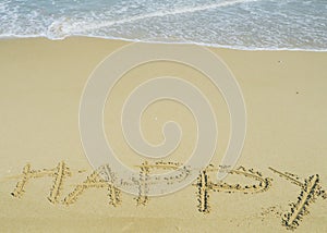 Happy wording written on sand next the sea. relaxing and enjoying summer vacation