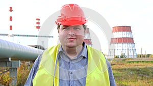 Happy worker, engineer, or electrician looking directly at the camera and smiling in front of a power station