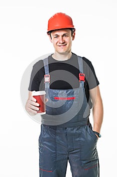 Happy worker in hard hat holding paper cup with coffee to go and smiling at camera isolated on white background