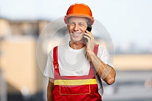 Happy worker in hard hat talking on phone.